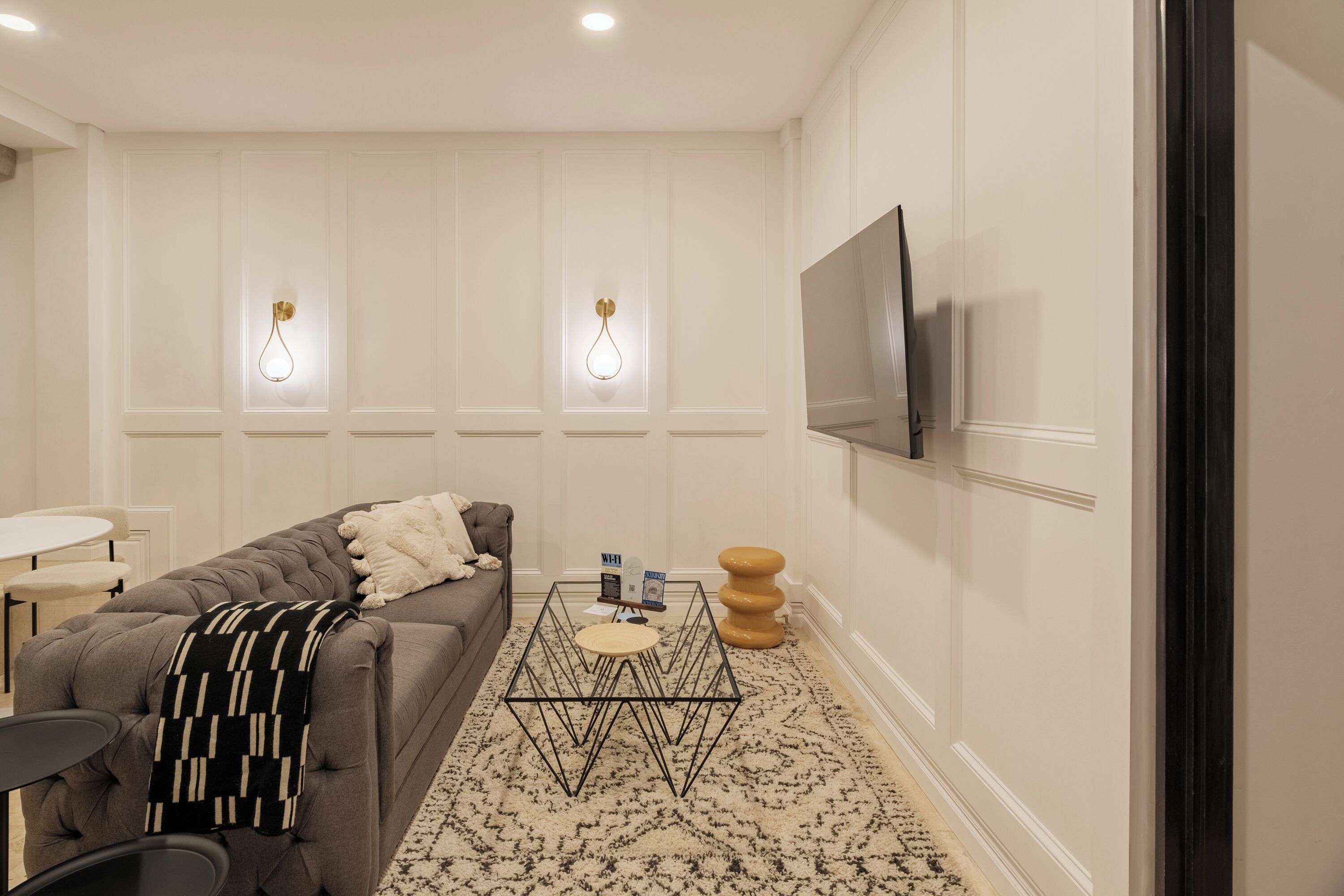 Un salon moderne avec un canapé, une table basse et un téléviseur à écran plat fixé au mur.