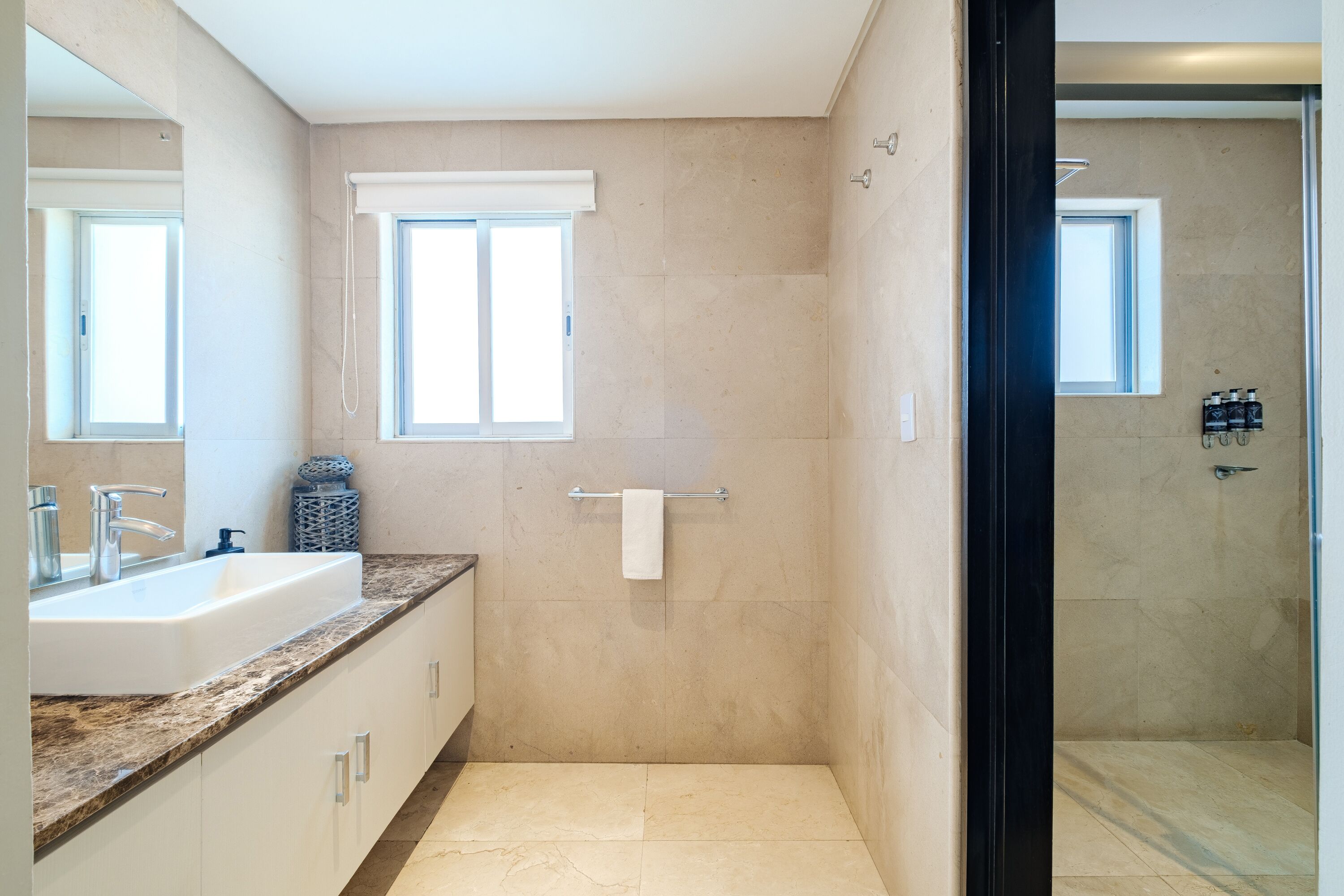A bathroom with a large sink, mirror, and a shower area.
