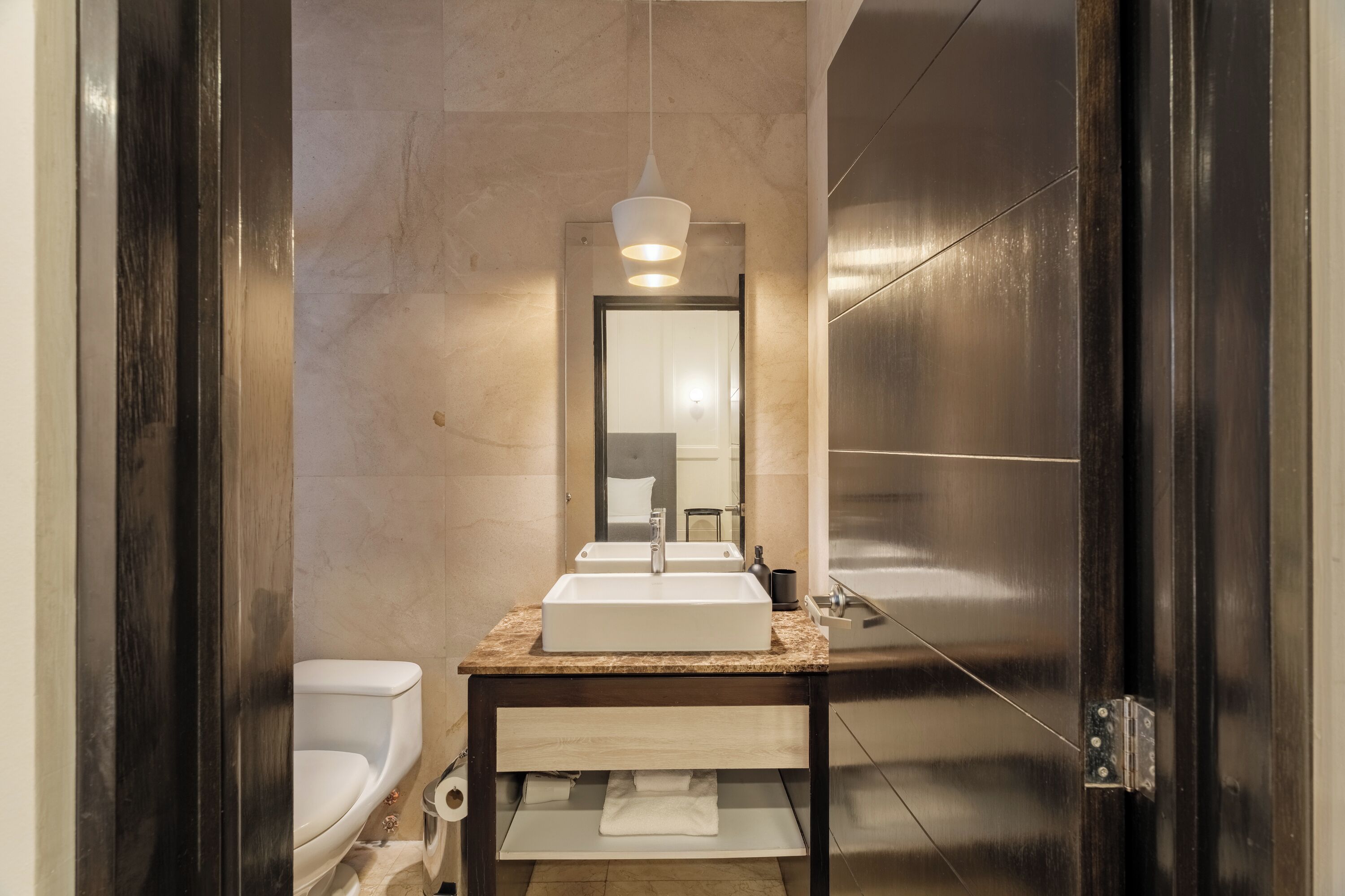 A modern bathroom with a white sink, a mirror, and a toilet.