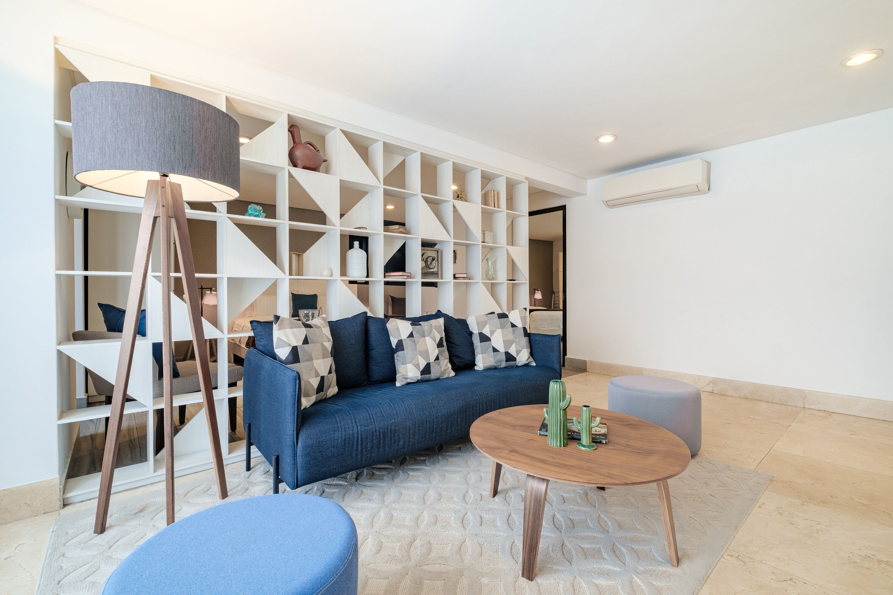 A modern living room with a blue sofa, a round wooden coffee table, and a floor lamp.