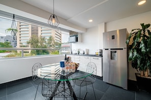 Uma cozinha moderna com área de jantar, grandes janelas e vista para edifícios.