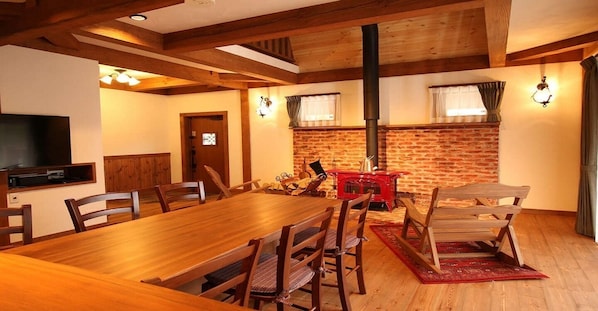 A dining area with a wooden table and chairs, a brick wall, and a red stove.