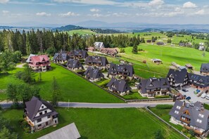 Zona residencial con casas alineadas, rodeada de campos verdes y árboles.