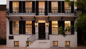 A two-story building with a balcony, a front door, and a staircase leading to the entrance.