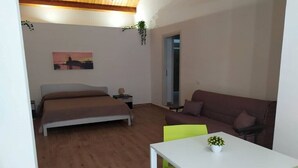 Ein Schlafzimmer mit Bett, einer Couch, einem Tisch und einem Gemälde an der Wand.