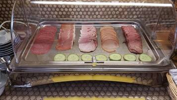 A food display case with sliced meats and cucumbers.