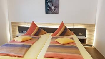 Uma cama de casal com manta degradê, duas almofadas e uma obra de arte na parede.