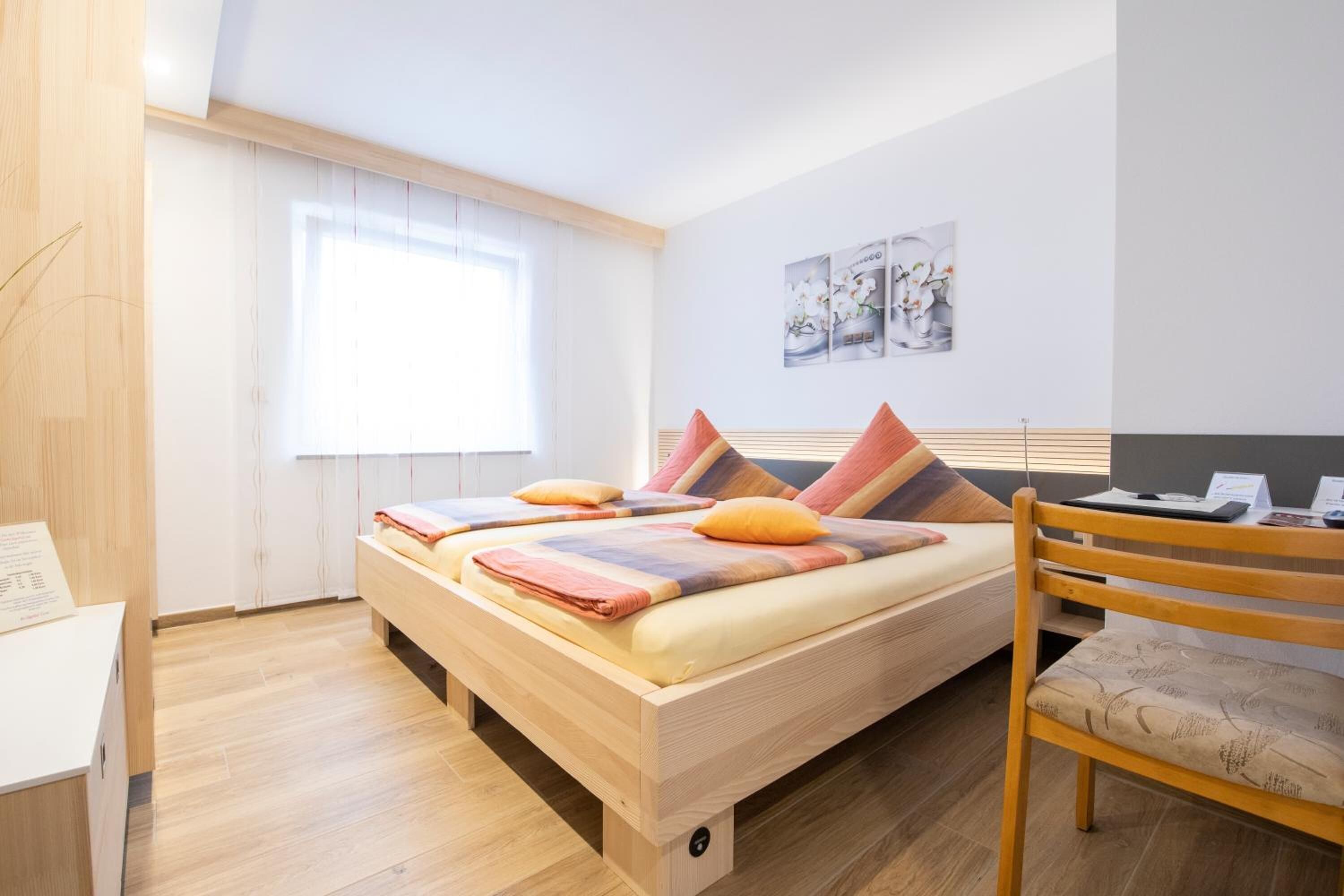 A modern bedroom with a wooden bed, a desk, and a chair.