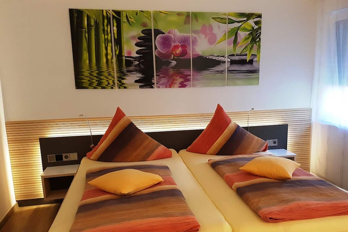 A modern bedroom with a bed, pillows, and a wall-mounted artwork.