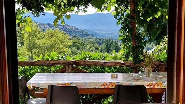 A table with chairs and a vase of flowers, set against a backdrop of a mountainous landscape. - Elcriso, Spacious villa, private pool, amazing views, WIFI, walk to restaurant! (Chiozza)