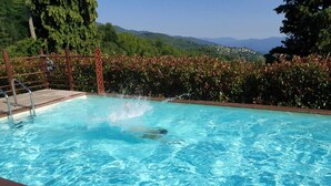 A swimming pool with clear blue water, surrounded by a wooden fence and a hedge. - Elcriso, Spacious villa, private pool, amazing views, WIFI, walk to restaurant! (Chiozza)
