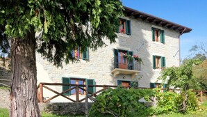 A stone building with green shutters, a balcony with flowers, and a tree in the foreground. - Elcriso, Spacious villa, private pool, amazing views, WIFI, walk to restaurant! (Chiozza)