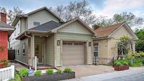 A two-story house with a front garage, a small porch, and a well-maintained garden.