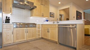 A modern kitchen with wooden cabinets, a stainless steel stove, and a dishwasher.