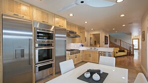 Una cocina moderna con electrodomésticos de acero inoxidable, armarios de madera y un comedor con mesa blanca.