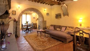 A cozy living room with a sofa, a dining table with chairs, and a fireplace. - Spacious Tuscan Villa with Large Pool near Castiglion Fiorentino. (Castiglion Fiorentino)
