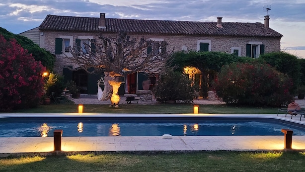A stone house with a swimming pool, surrounded by lush greenery and flowering plants. - Mas La Pomarède (Robion)