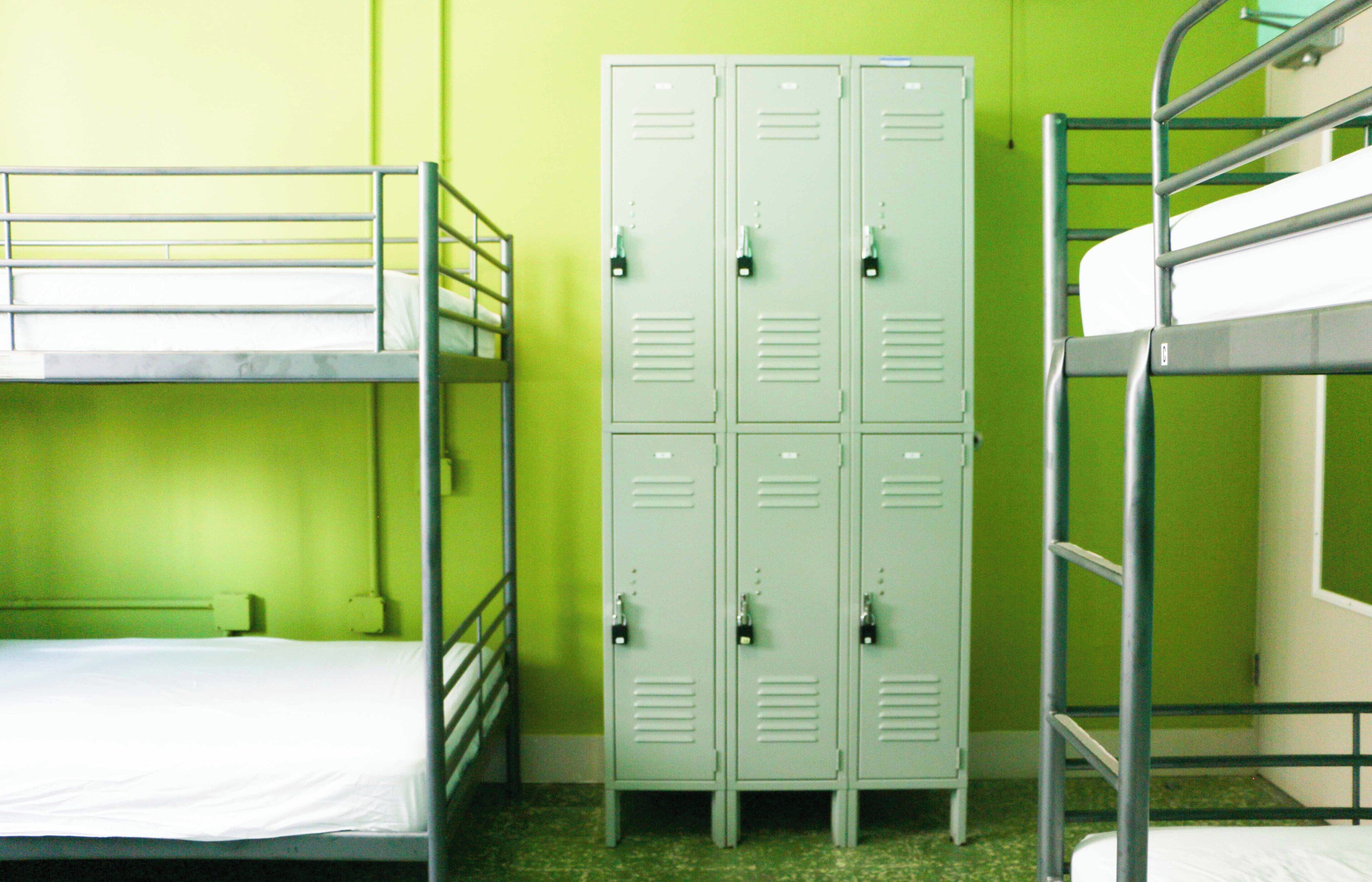 A bunk bed room with two bunk beds, a set of lockers, and a green wall.