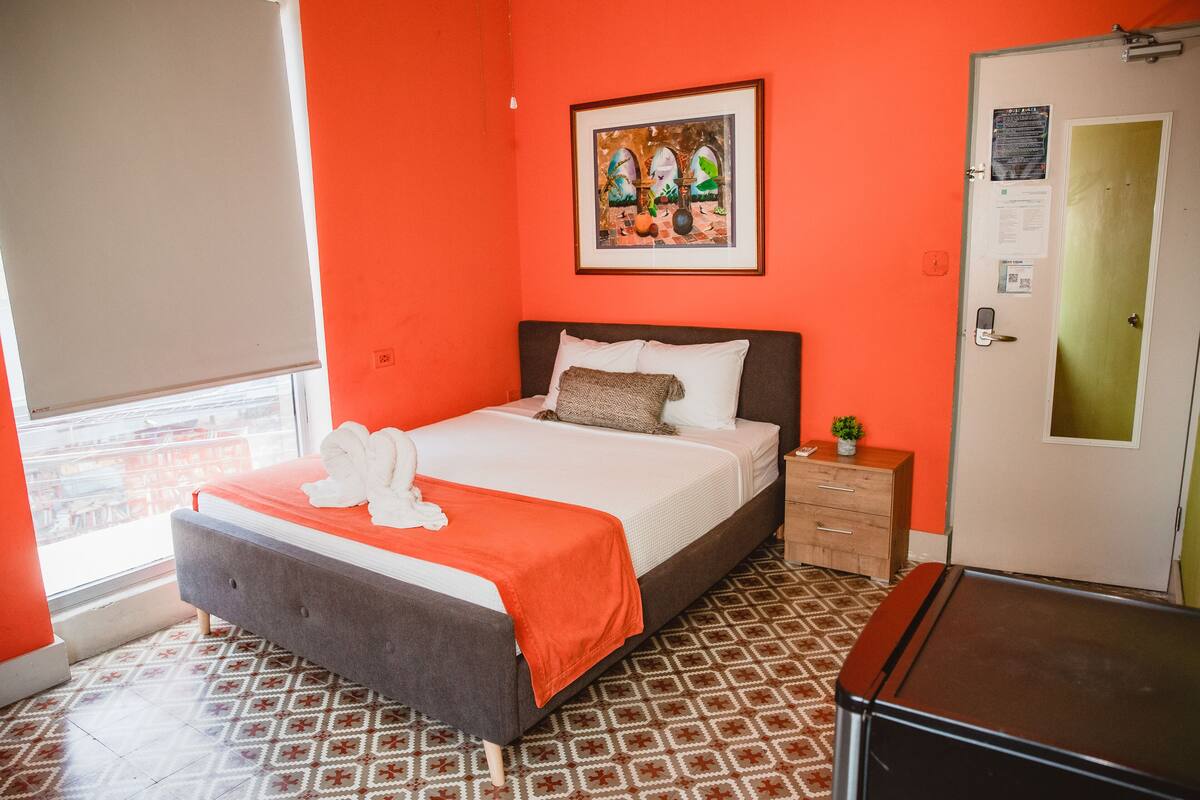 Una habitación de hotel con una cama, un tocador, una puerta y una ventana.