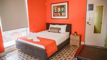Una habitación de hotel con una cama, un tocador, una puerta y una ventana.
