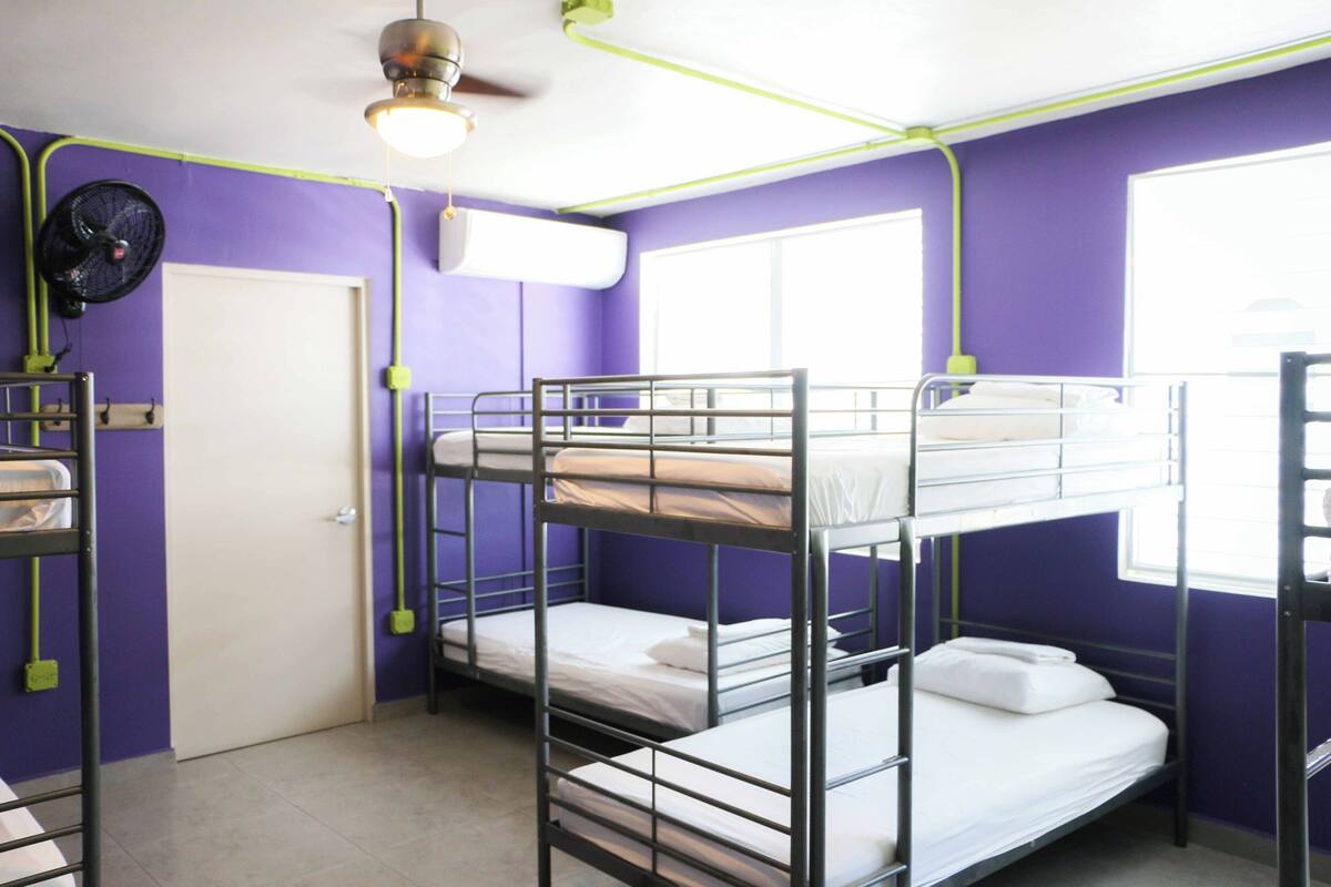 Un dormitorio con literas, un ventilador, una ventana y una puerta.