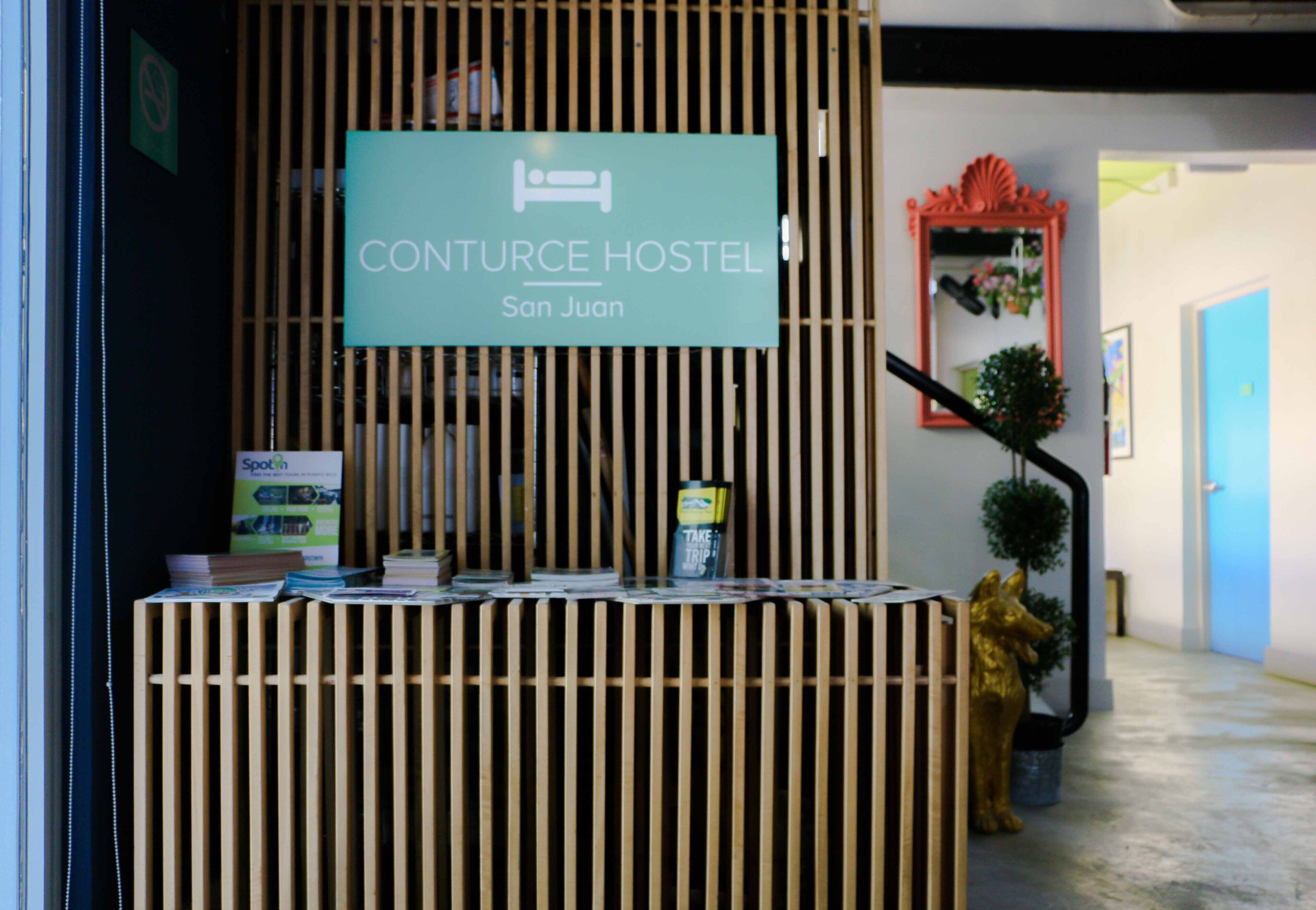 A reception desk with a sign for Conturce Hostel in San Juan.