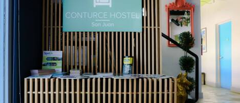 A reception desk with a sign for Conturce Hostel in San Juan.