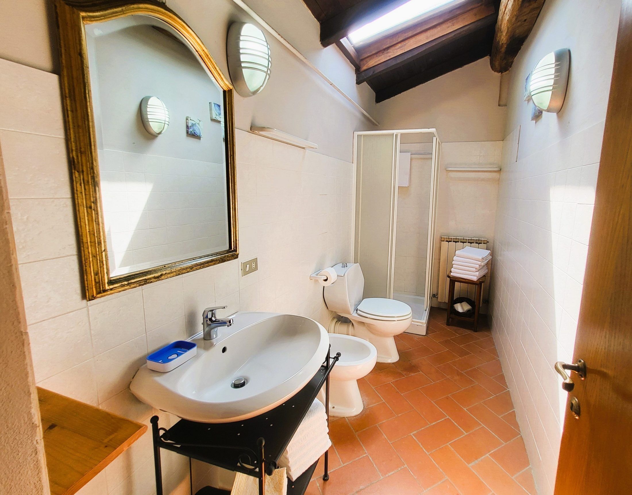 A compact bathroom with a sink, mirror, and two toilets.