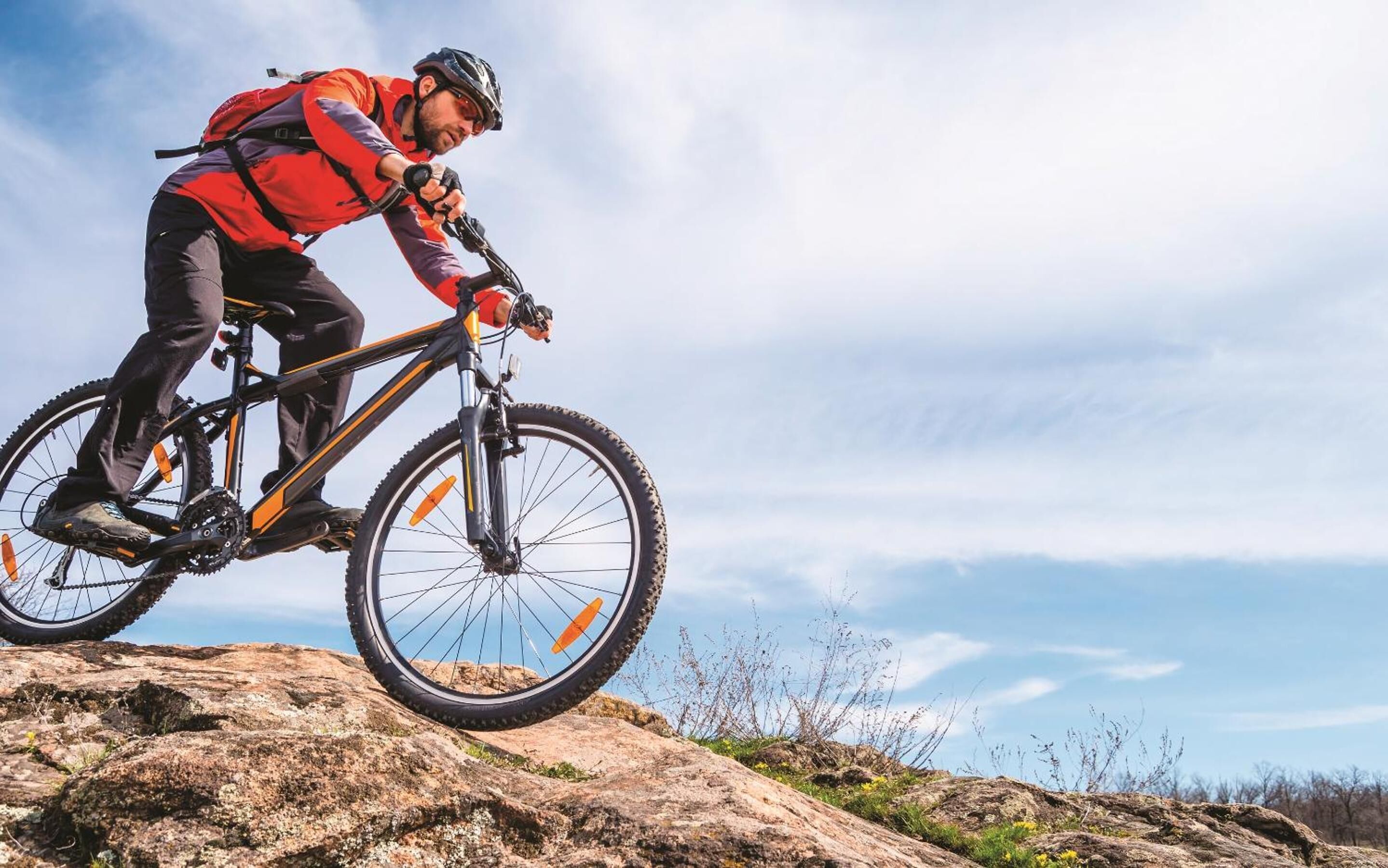 Una persona montando una bicicleta de montaña sobre terreno rocoso.
