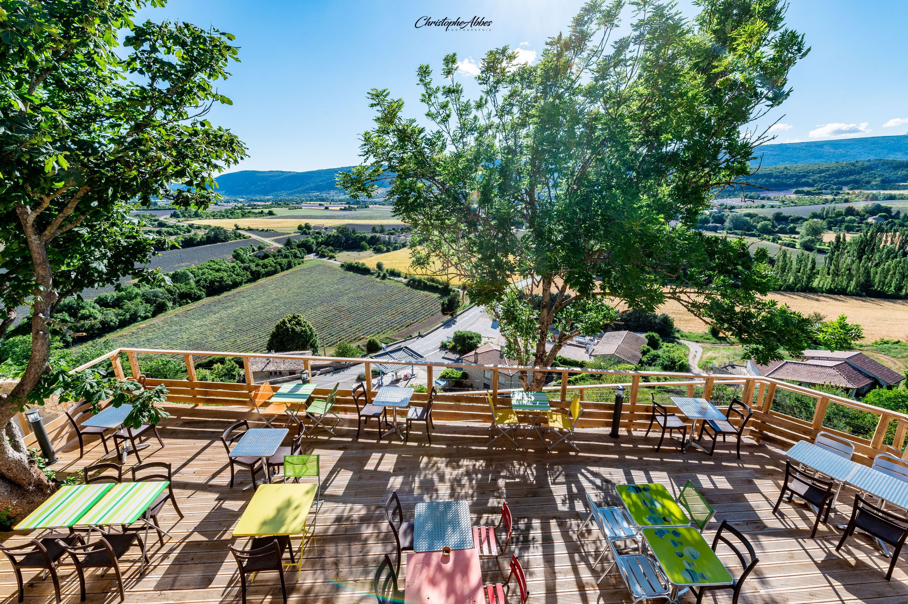A wooden deck with outdoor seating and a scenic view of a vineyard and hills.