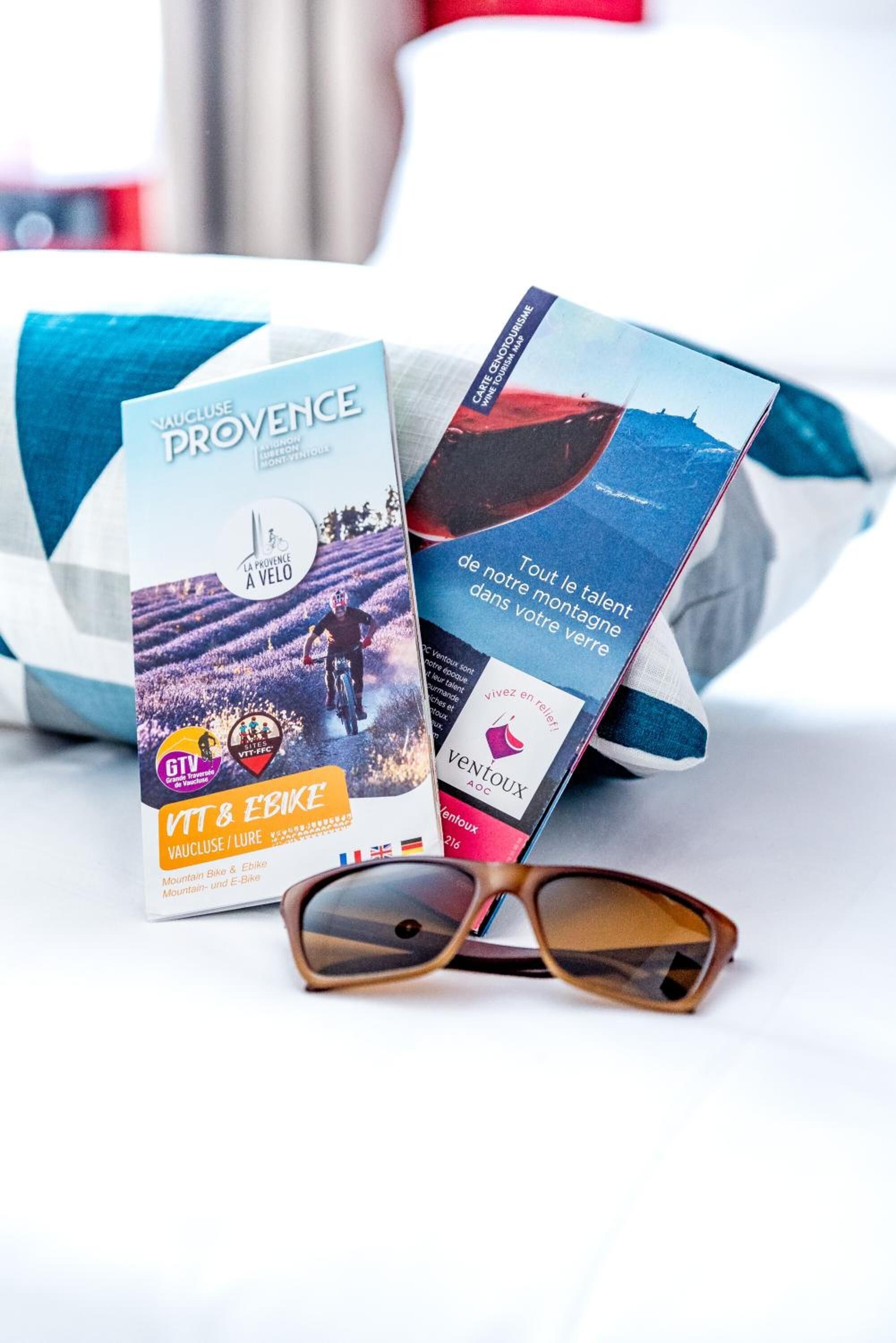 Un folleto con el título 'Vaucluse Provence' y un par de gafas de sol sobre una cama.