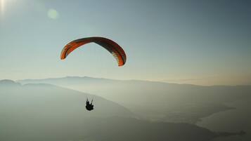 Ein Gleitschirmflieger über einer gebirgigen Landschaft.