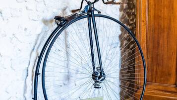 A vintage bicycle leaning against a textured wall with a wooden cabinet nearby.
