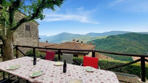 An outdoor dining area with a table set for two, overlooking a mountainous landscape. - Palazzo  Pasquini, stunning views/sunsets, private pool, WIFI, chef option!  (Treppignana Fosciandora)