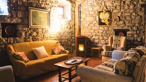 A cozy living room with a stone wall, a fireplace, and a sofa with patterned cushions. - Palazzo  Pasquini, stunning views/sunsets, private pool, WIFI, chef option!  (Treppignana Fosciandora)