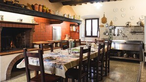 A traditional kitchen with a brick oven, wooden chairs, a dining table set for four, and various kitchen utensils and dishes on shelves. - Palazzo  Pasquini, stunning views/sunsets, private pool, WIFI, chef option!  (Treppignana Fosciandora)