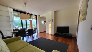 A modern living room with a sofa, a TV, and a dining area with a table and chairs. - Luxury villa, mountain views, private pool, WiFi & chef night option! (Nicciano)