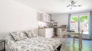 A bedroom with a bed, a small kitchenette, and a dining area with a table and chairs. - The Maison Rose studio (Callas)