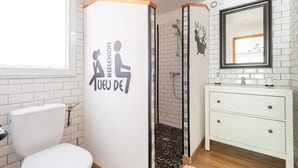 A bathroom with a white toilet, a sink with a mirror, and a shower with a tiled wall. - The Maison Rose studio (Callas)