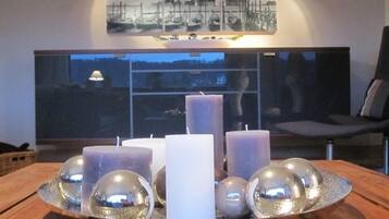 A table with candles and reflective spheres, a cityscape view through a window, and a framed picture on the wall.