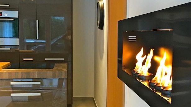 Eine moderne Küche mit eingebautem Kamin, glattem Korpus und einem Edelstahlbackofen.