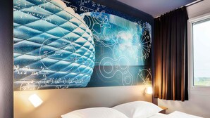 A hotel room with a large wall mural of mathematical equations and a bed with white linens. - B&B Hotel München-Garching (Garching)