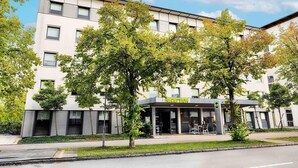 A modern building with a reception area and multiple windows. - B&B Hotel München-Garching (Garching)