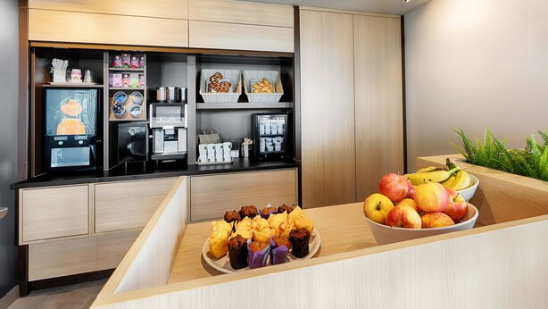 A modern kitchen with a wooden countertop, a coffee machine, and a fruit bowl. - B&B Hotel München-Garching (Garching)