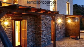 A modern house with a stone facade, wooden beams, and a stone staircase leading to the entrance. - Pool garden house (Kea)