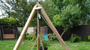 A backyard with a swing set, a fire pit, and a wooden swing. - romantic Oberstübchen (Norden)