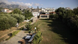 A residential area with a paved pathway, a scooter, and a table with a chair. - Kalliopi Hotel (Minoa Pediada)