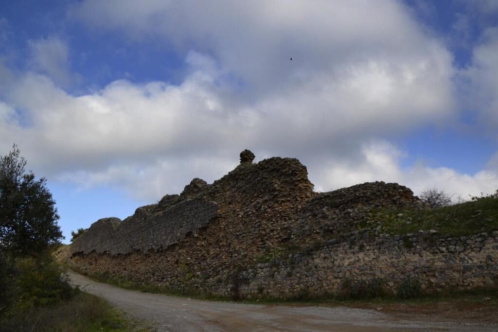Uma estrada de terra que leva a uma grande colina rochosa com vegetação escassa.