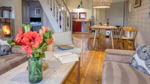 A cozy living room with a fireplace, a dining area with a table and chairs, and a staircase leading to an upper level. - traumHaff® Sea Hideaway, private NORDICSPA, fireplace, dog, 200m from the water (Rieth am See)