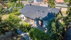 A traditional house with a sloped roof, a front porch, and a view of a lake. - traumHaff® Sea Hideaway, private NORDICSPA, fireplace, dog, 200m from the water (Rieth am See)